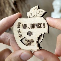 a person holding an apple shaped brooch with the words mr johnson on it