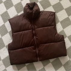 This Cropped Puffer Vest Jacket Features A Sleeveless Design, Stand Collar To Block Wind, Loose Fitting Shoulders And Waist, And Finished With An Elastic Adjustable Drawstring Hem. It’s Great For Daily Wear Or Outdoor Activities, Such As A Date, Shopping, Hangouts, Or Running. Solid Puffer Sleeveless Vest, Brown Sleeveless Vest For Cold Weather, Trendy Brown Winter Vest, Cropped Puffer Vest, Puffer Vest Jacket, Design Stand, Puffer Vest, Chocolate Brown, Stand Collar