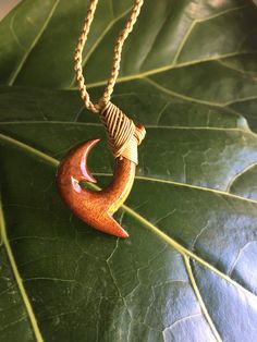 a wooden crescent pendant sitting on top of a leaf