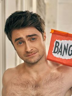 a shirtless man holding up a bag with the word bang on it in front of his face