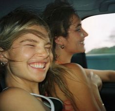 two women are sitting in the back seat of a car and one has her eyes closed