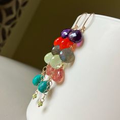 New gemstone mix!   From the top: purple Amethyst,  Carnelian, Labradorite, pale green Prehnite, Strawberry quartz, Chrysocolla, Peridot. These dreamy gems are all suspended from 14k yellow goldfilled links and earwires.   Gems measure approximately 8-10mm wide. Total earring length is 2 + 11/16 inches. Please note that pictures of my jewelry are enlarged. The gemstone colors may vary on the device being used to view items. I do not alter the gemstone colors in my photos, but the backdrop can alter their look. My practice is always to add my jewelry last before heading out and to remove my jewelry first after returning home. Here are a few other jewelry care tips: Avoid direct contact with perfume, hairspray or other chemicals. Remove jewelry when bathing, showering or swimming. Remove jew Bohemian Gemstone Earrings For Everyday, Purple Multi-stone Bohemian Jewelry, Bohemian Everyday Gemstone Earrings, Purple Bohemian Multi-stone Jewelry, Purple Bohemian Everyday Jewelry, Unique Multicolor Gemstone Earrings, Natural Briolette Gemstones In Bohemian Style, Bohemian Briolette Gemstones, Bohemian Briolette Gemstone Earrings