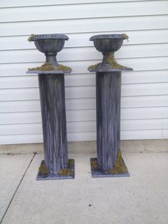 two metal vases sitting next to each other on the side of a building near a door