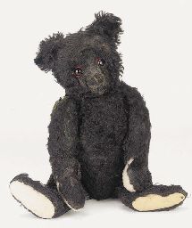 a black teddy bear with red eyes sitting on the ground and looking at the camera