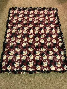 a red and white blanket with black trim on the floor next to a brown carpet