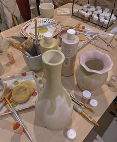 the table is covered with pottery and other crafting supplies, such as paintbrushes