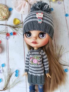 a doll with long hair wearing a gray and white striped sweater, jeans and boots