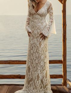 a woman standing on top of a wooden pier next to the ocean wearing a white dress