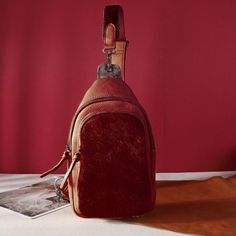 a small brown purse sitting on top of a white table next to a red wall