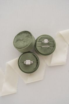 three wedding rings sitting on top of each other in velvet cases with satin ribbons around them