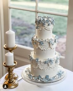 a three tiered cake sitting on top of a table next to a candle holder