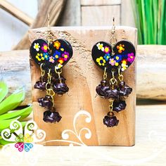 a pair of black heart shaped earrings with colorful flowers hanging from it's sides