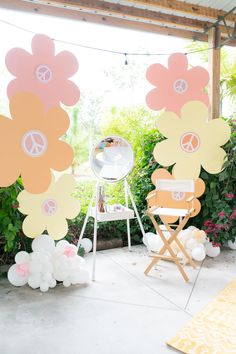 an outdoor party with flowers and balloons on the ground, in front of a sign that says peace