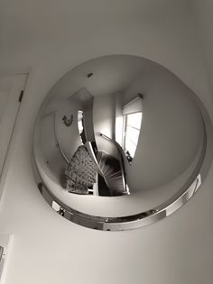 a circular mirror hanging on the side of a wall next to a doorway and stairs