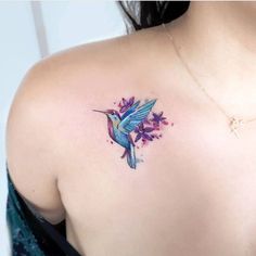 a woman's back shoulder with a watercolor hummingbird tattoo on her left shoulder