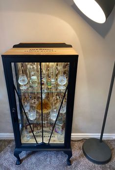 an old fashioned glass cabinet with liquor bottles in it and a lamp on the side