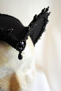 This is a purple and black version of one of most successful designs called Countess. This vampire style headdress is covered with dark purple taffeta and embellished with black cord trimming all around the edges.It is further trimmed with black crystal details that create a halo effect as well as small l beads that were hand-sewn on the trimming to create rich textural interest. The piece is completed with a black crystal handmade element placed at the center front for all that extra drama that Witchy Black Costume Hats For Cosplay, Black Medieval Costume Accessories For Cosplay, Medieval Black Costume Accessories For Cosplay, Black Medieval Costume Accessories For Costume Party, Adjustable Black Costume Accessories For Fantasy Events, Black Medieval Costume Accessories For Parties, Halloween Cosplay Costume Accessories With Tall Crown, Gothic High Crown Costume Hat For Cosplay, Fantasy Crown Costume Accessory