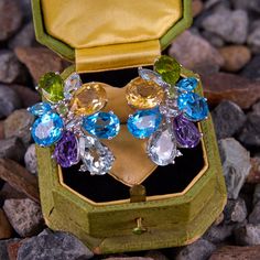 This fun and colorful pair of earrings are each accented with three (3) natural blue topaz, one (1) natural aquamarine, two (2) natural peridot, one (1) natural citrine, one (1) natural amethyst, one (1) natural prasiolite, and five (5) diamonds all set into prong settings. The earrings measure 32.3mm X 24.6mm and are finished with posts and 14k white gold friction backs. Anniversary Blue Topaz Multi-stone Earrings, Anniversary Multi-stone Blue Topaz Earrings, Multi-stone Blue Topaz Earrings As Gift, Elegant Multi-stone Topaz Gemstones, Fine Jewelry Topaz Earrings With Gemstone Accents, Multi-stone Topaz Gemstones As Gift, Natural Citrine, Natural Aquamarine, One 1