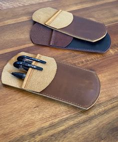 two brown and black pen cases sitting on top of a wooden table