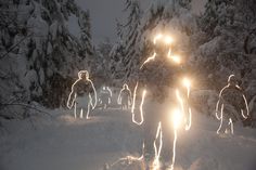 several people are walking through the snow at night with their head lights glowing on them