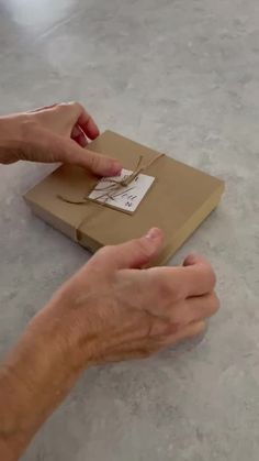 two hands reaching for a piece of cardboard with a tag on it