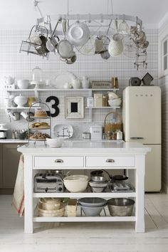 a white kitchen with lots of pots and pans hanging from the ceiling above it