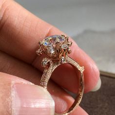 a close up of a person's hand holding a ring with diamonds on it