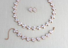 a necklace and earring set on a white cloth with a gold chain around it