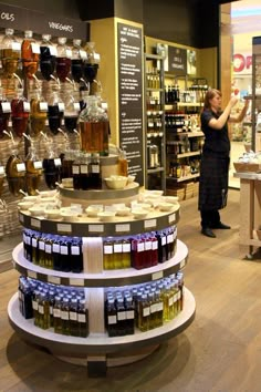 a woman standing in front of a store filled with lots of bottles and jars full of liquid