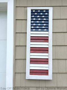 an american flag is hanging on the side of a house in front of a window