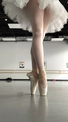 a ballerina's feet in white tutu and ballet shoes on the floor