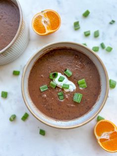 two bowls filled with soup next to an orange slice