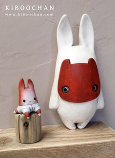 two ceramic rabbits sitting next to each other on a wooden shelf with a wall in the background