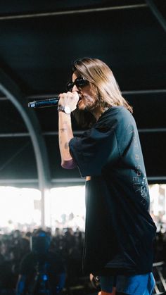 a man with long hair and beard standing on stage holding a microphone to his mouth