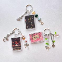 four different key chains with pictures and charms attached to them on a white table top