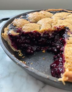 a blueberry pie in a pan with one slice cut out and ready to be eaten