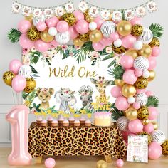 an animal themed birthday party with pink, gold and white balloons on the wall next to a leopard print tablecloth