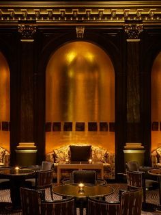 the interior of a fancy restaurant with gold walls and black tables, chairs, and couches