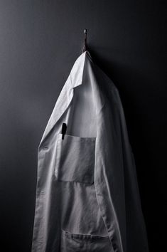 a piece of white paper hanging from a hook on a wall next to a coat rack