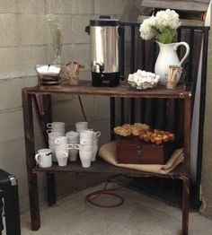 a table with coffee cups and pastries on it in front of a building wall