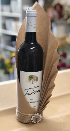 a bottle of wine sitting on top of a table next to a brown paper bag