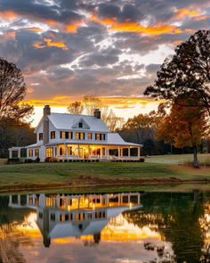 a large white house sitting on top of a lush green field next to a lake