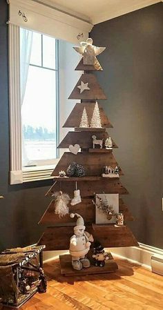 a wooden christmas tree sitting on top of a hard wood floor next to a window