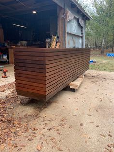 a large wooden boat sitting in the middle of a yard next to a shed with tools on it