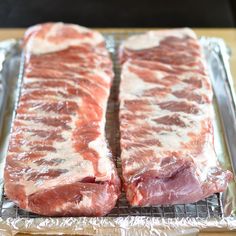 two pieces of raw meat sitting on top of a metal pan