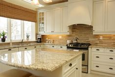 a kitchen with marble counter tops and white cabinets