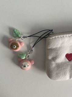 three little bears are attached to a small pouch with a keychain that has a heart on it