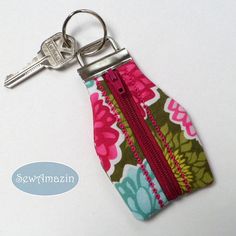 a keychain with a zipper on it sitting next to a pair of keys