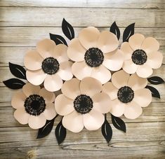 an arrangement of paper flowers arranged on a wooden surface with black leaves and petals in the center