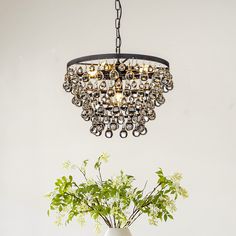 a chandelier hanging from the ceiling over a vase with flowers in it on a table